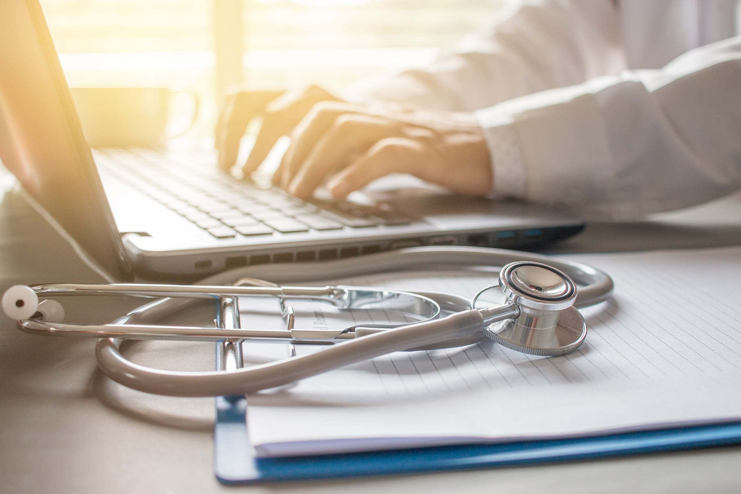 Stethoscope on prescription clipboard and Doctor working an Laptop on desk in hospital, Healthcare and medical concept, vintage color, selective focus